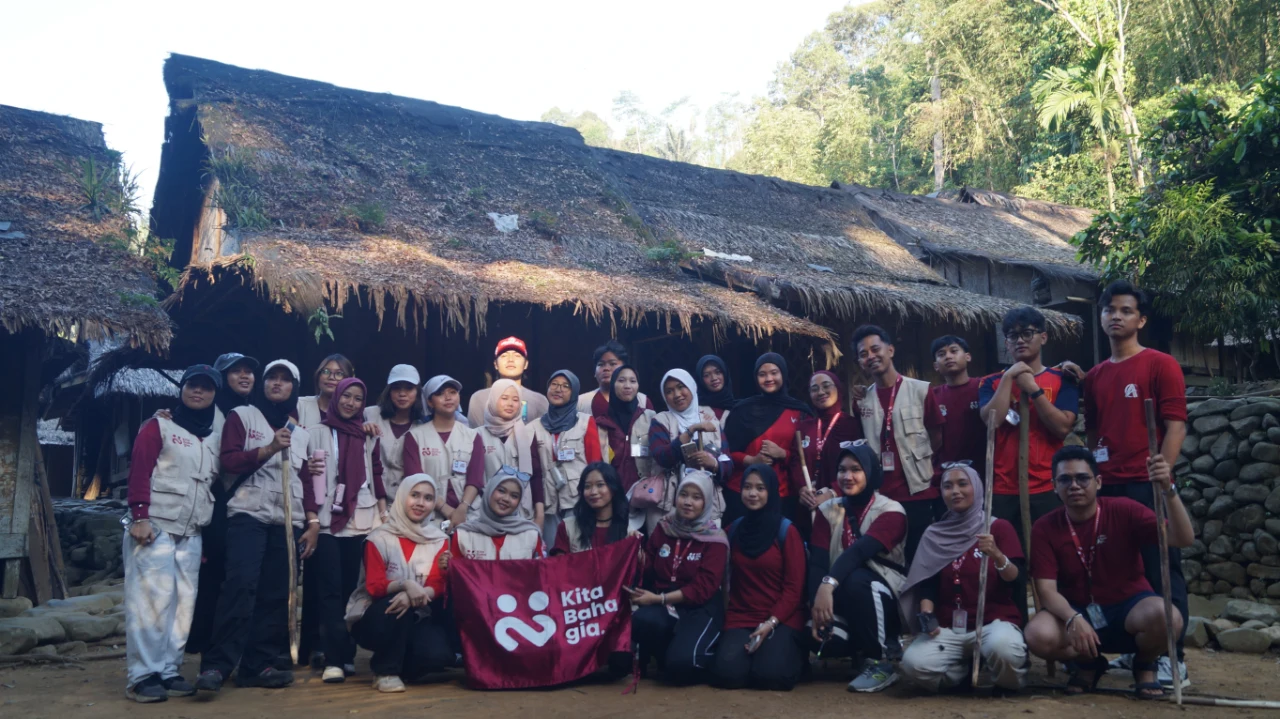Relawan dan peserta berfoto di depan rumah adat